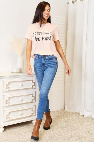 Woman wearing a slogan graphic cuffed T-shirt and jeans in a casual setting.