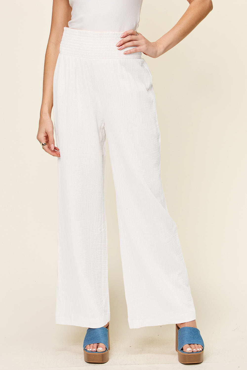 White smocked waist wide leg pants made of 100% cotton, featuring an opaque texture, styled with blue platform sandals.