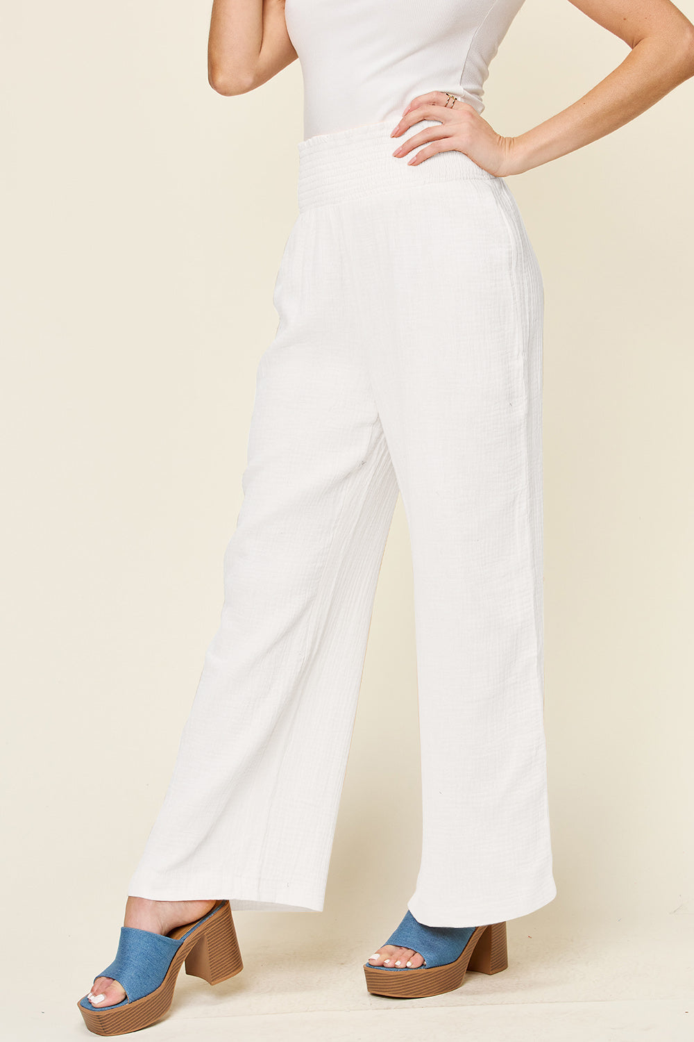 White smocked waist wide leg pants made of 100% cotton, featuring an opaque texture and stylish design for comfortable wear.