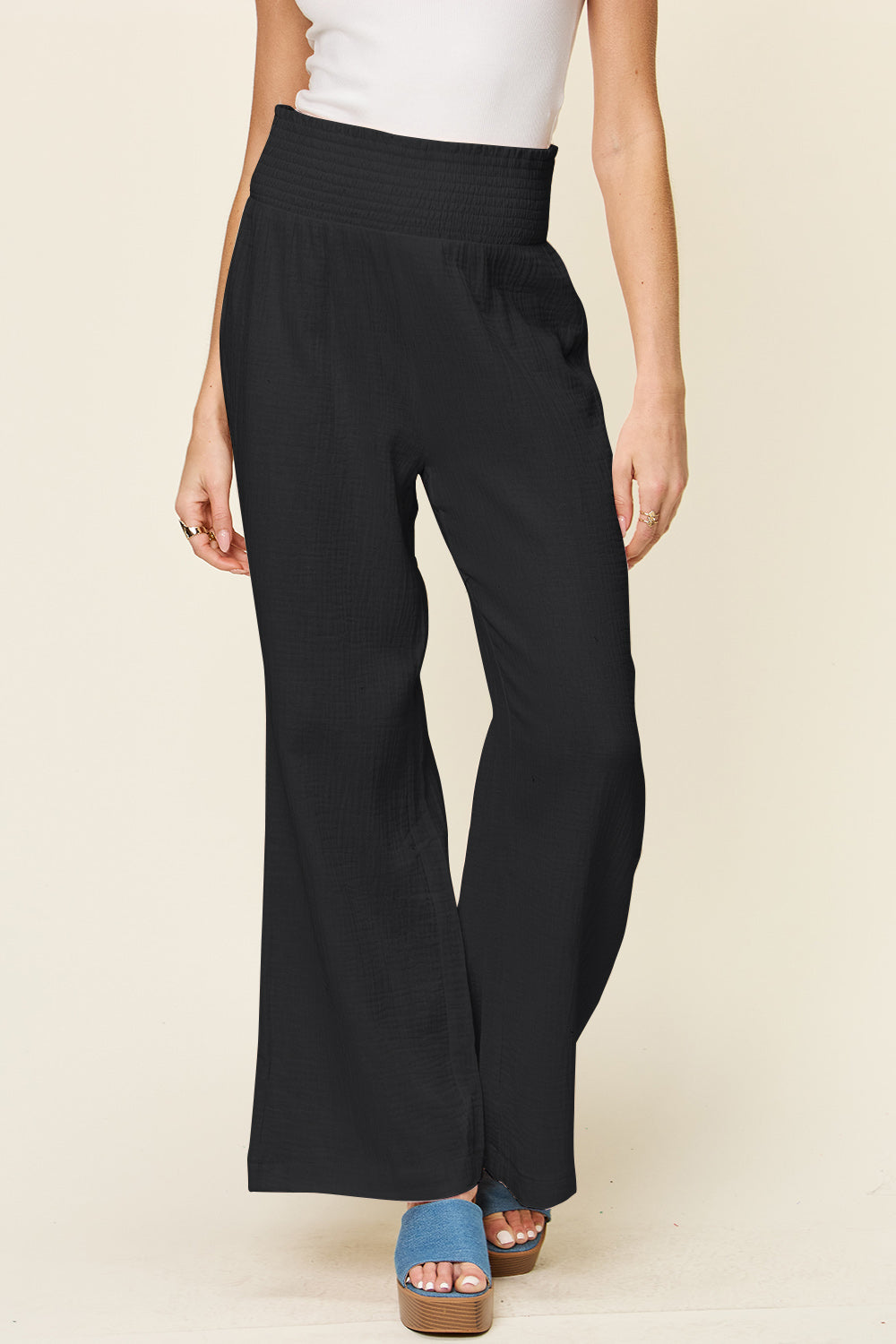 Black smocked waist wide leg pants made of 100% cotton, featuring a stylish and comfortable design for casual wear.