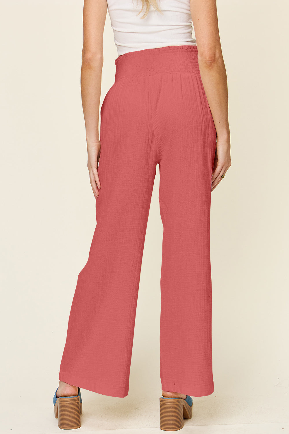 Woman wearing Texture Smocked Waist Wide Leg Pants in coral, 100% cotton, showcasing back view for casual fashion.