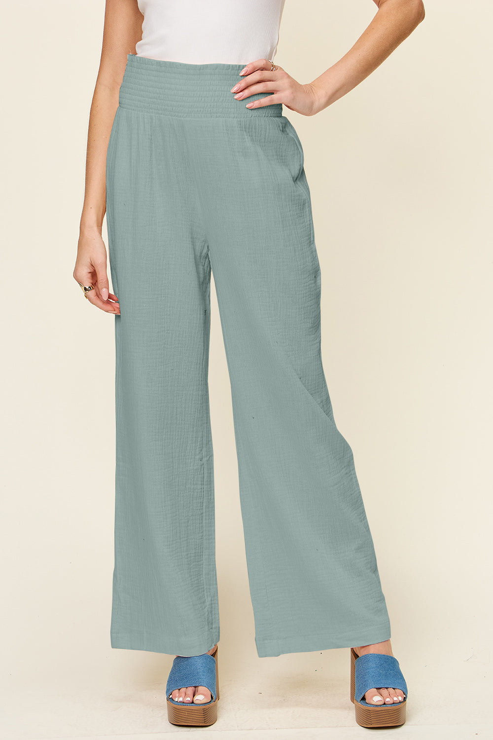 Woman wearing texture smocked waist wide leg pants, 100% cotton, with blue platform sandals.