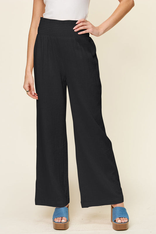 Black texture smocked waist wide leg pants made of 100% cotton, featuring a stylish and comfortable opaque design.