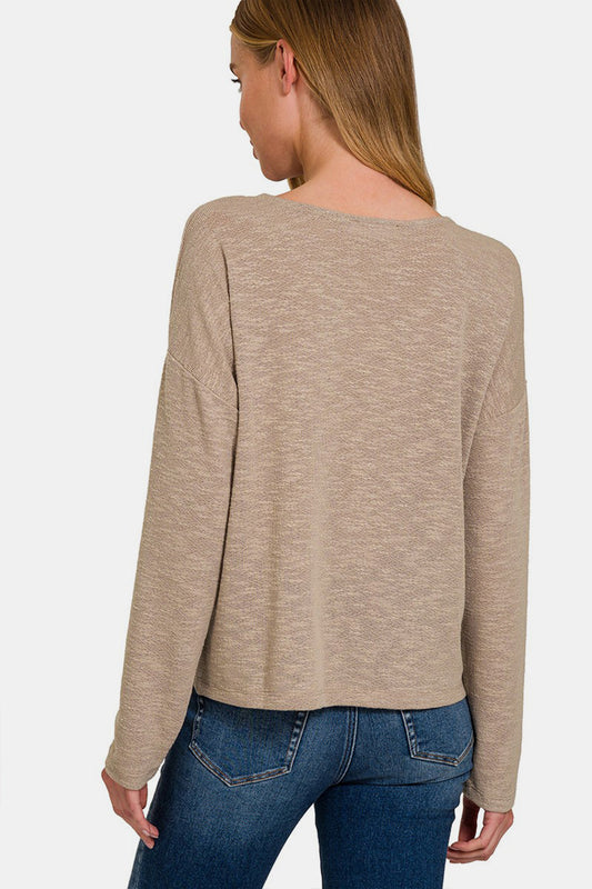 Woman wearing a beige dropped shoulder long sleeve t-shirt, back view, paired with jeans.