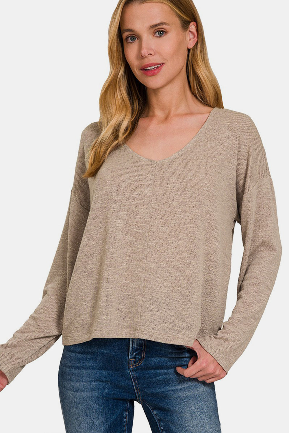 Woman wearing a dropped shoulder long sleeve t-shirt in beige with jeans, showcasing casual style and comfort.