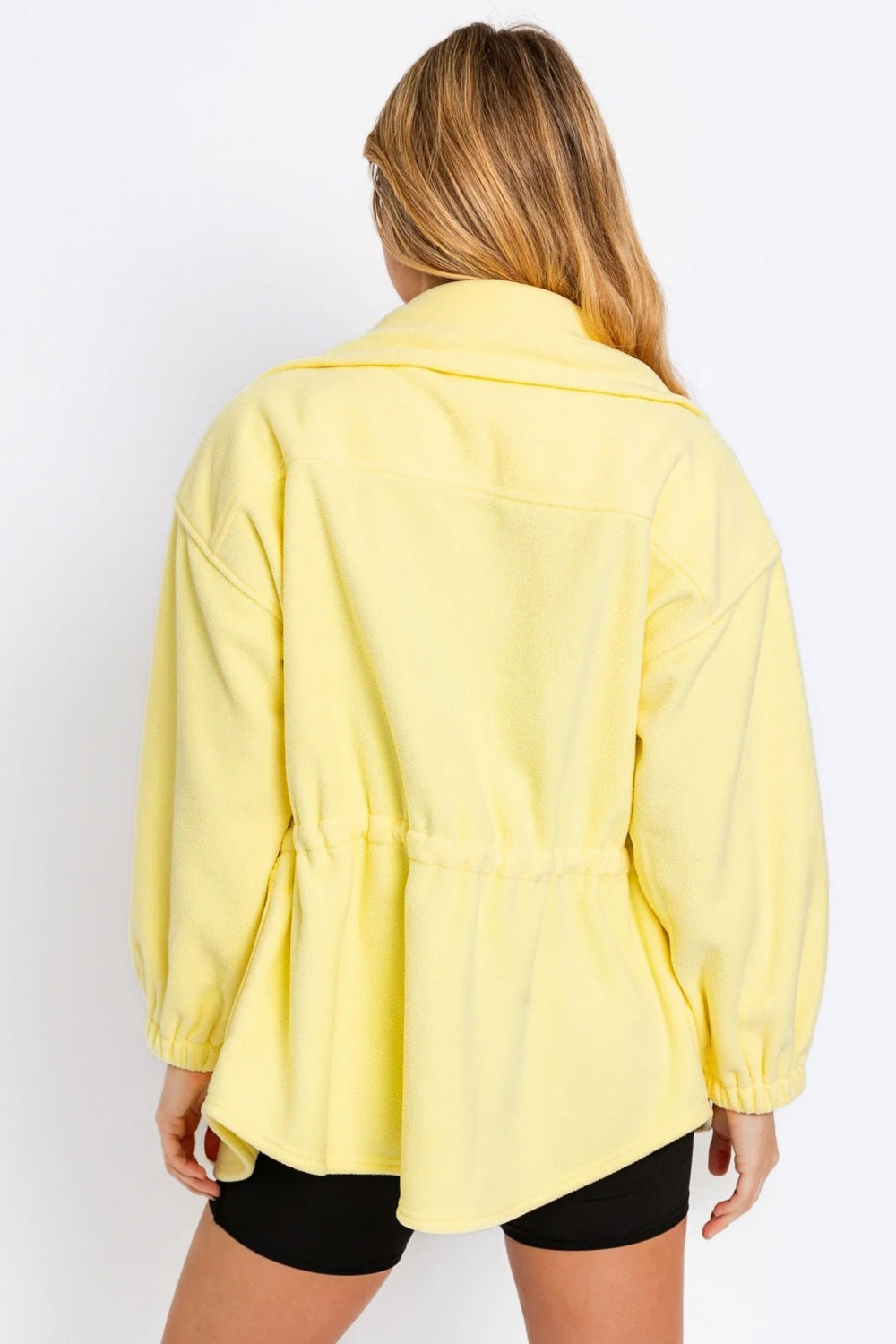 Yellow zip up waist drawstring soft fleece jacket with ruched detailing, shown from the back on a model wearing black shorts.