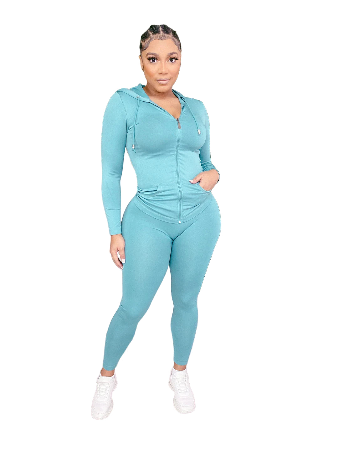 Woman wearing a solid hoodie leggings set in teal, standing in front of a green foliage backdrop with string lights.