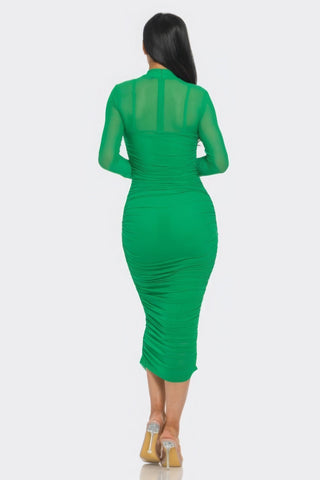 Woman wearing a green ruched midi dress with long sleeves and smock neck, showcasing a flattering silhouette.