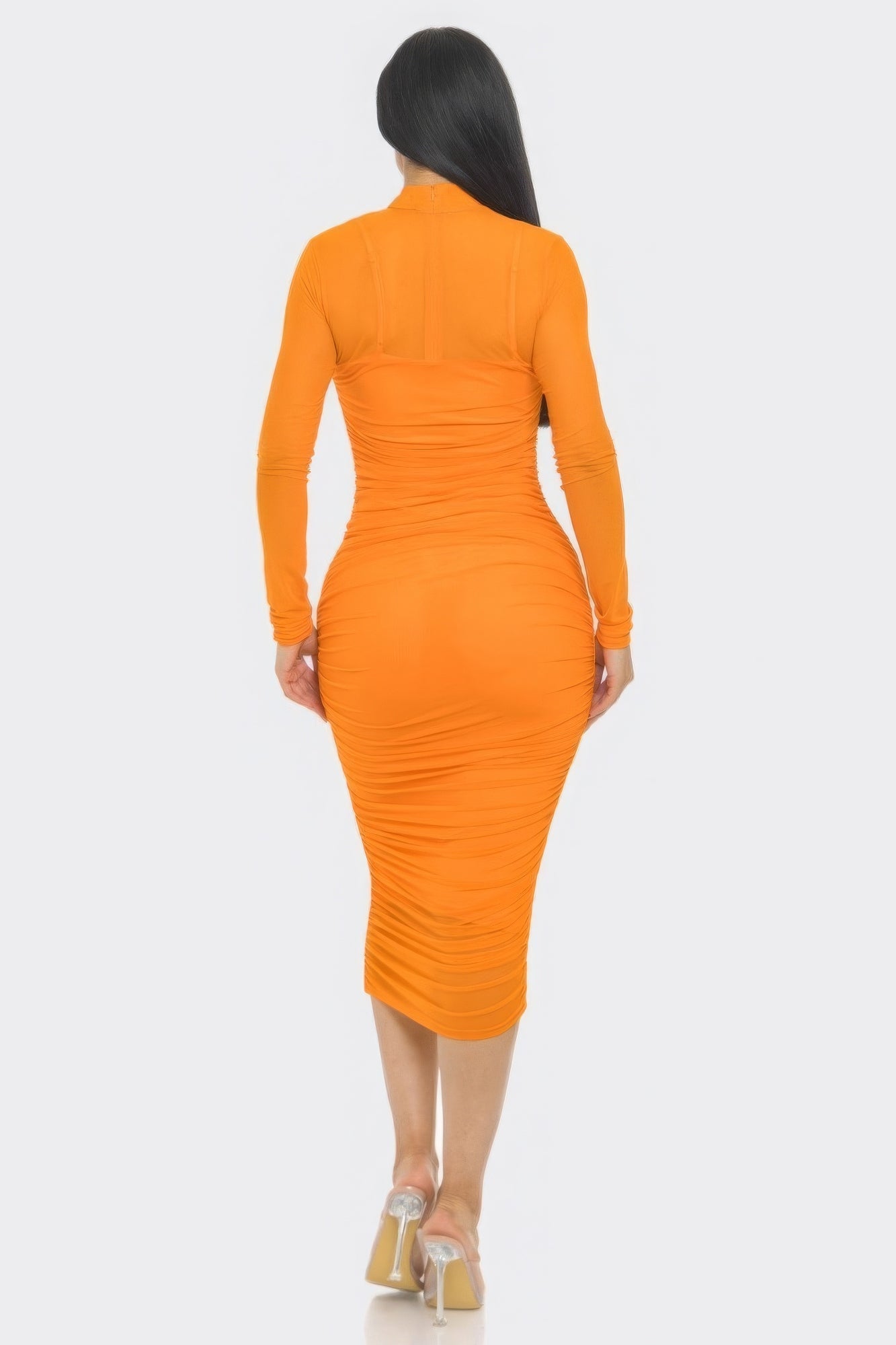 Woman wearing orange midi dress with ruched design and long sleeves, showcasing rear view and elegant silhouette.