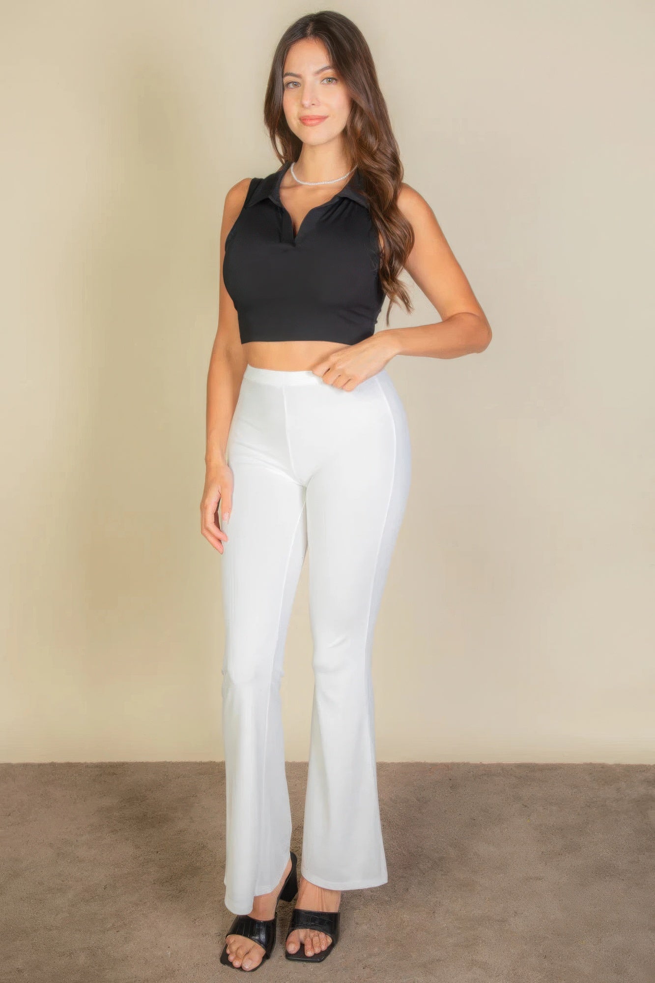Woman wearing black solid ribbed polo neck tank top and white pants in a chic, stylish outfit ensemble.