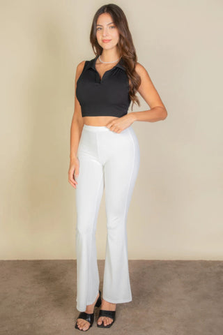 Woman wearing black solid ribbed polo neck tank top and white pants in a chic, stylish outfit ensemble.