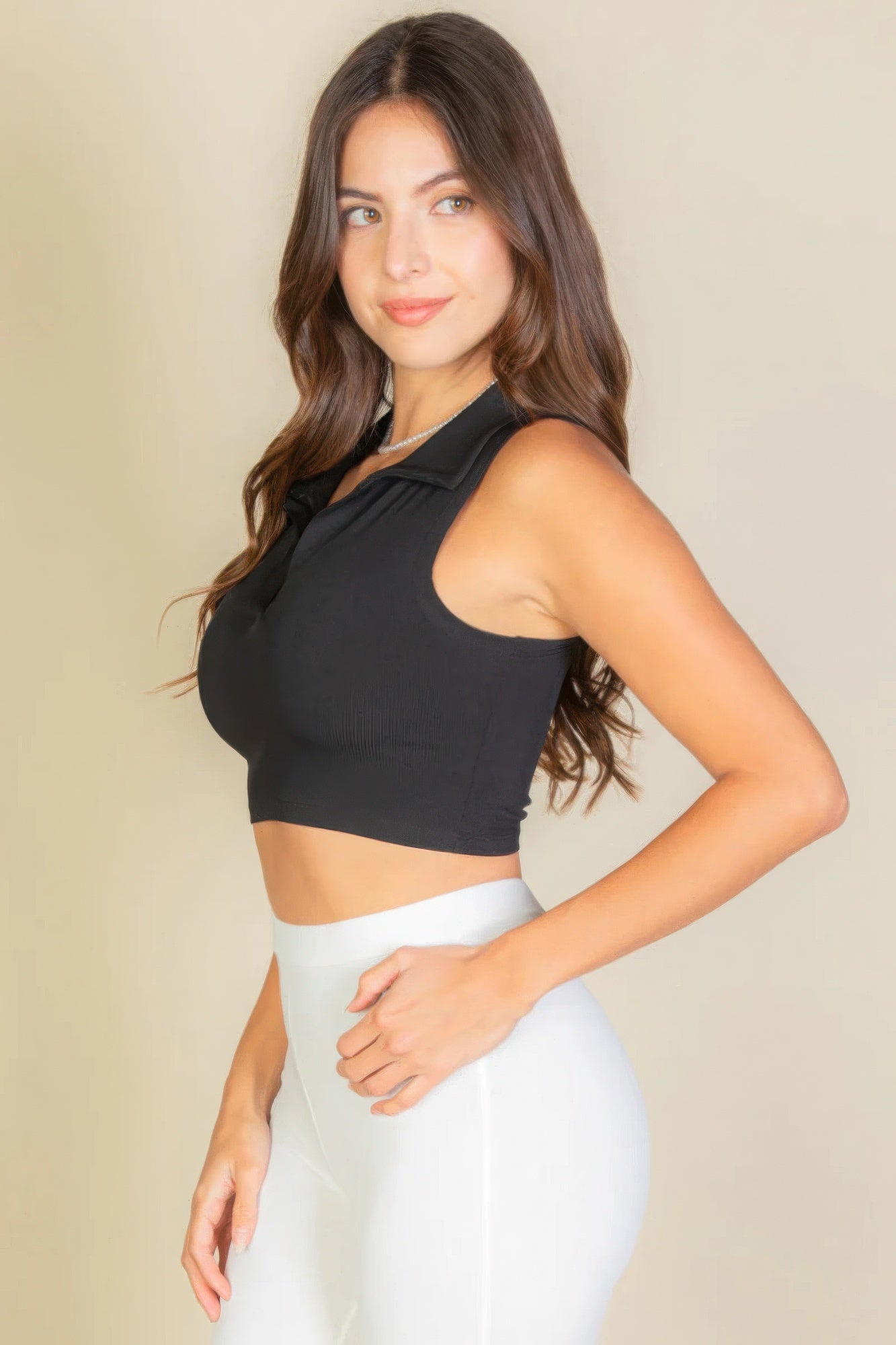 Woman wearing black solid ribbed polo neck tank top with sleek silhouette, showcasing chic and trendy style.