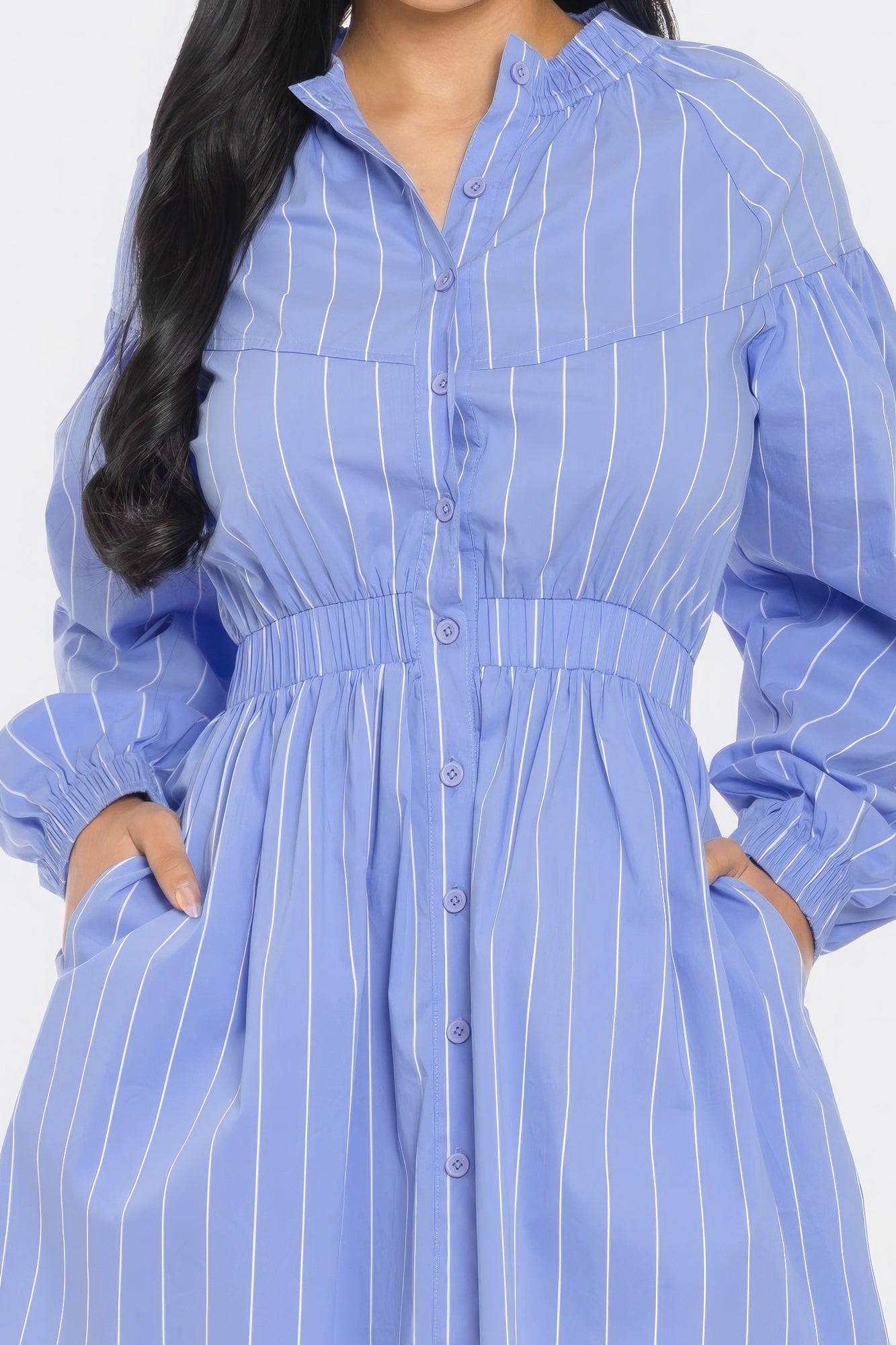 Woman wearing a blue and white striped mini dress with long sleeves and a flattering fit and flare silhouette.