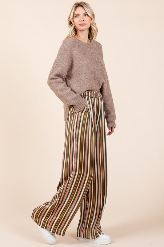 Woman wearing striped satin elastic waist wide leg pants with pockets.