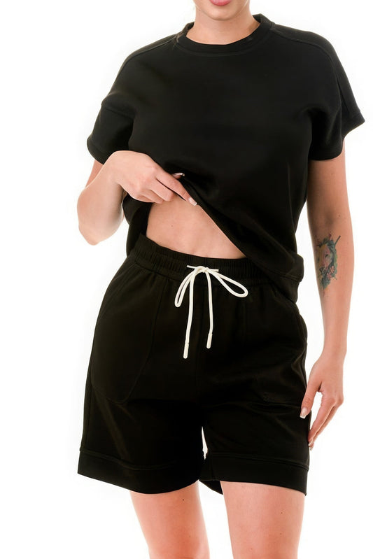 Woman wearing black monochrome tee and shorts set, showcasing comfortable, breathable fabric with stylish trim detailing.