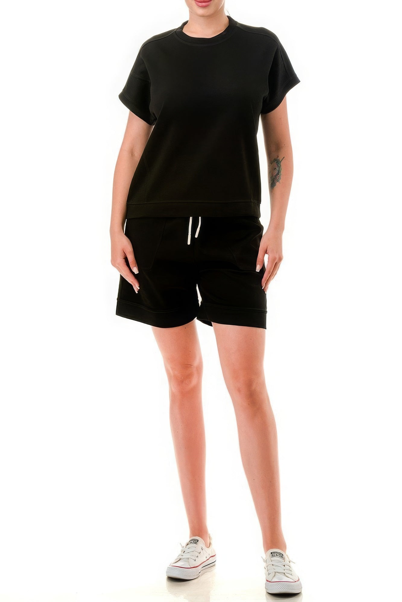 Woman wearing a black monochrome tee and shorts set made of lightweight air cotton fabric with a round neck and relaxed fit.