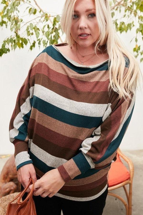 Woman wearing a boat neck knit top with multi-colored stripes and long bubble sleeves, standing outdoors.