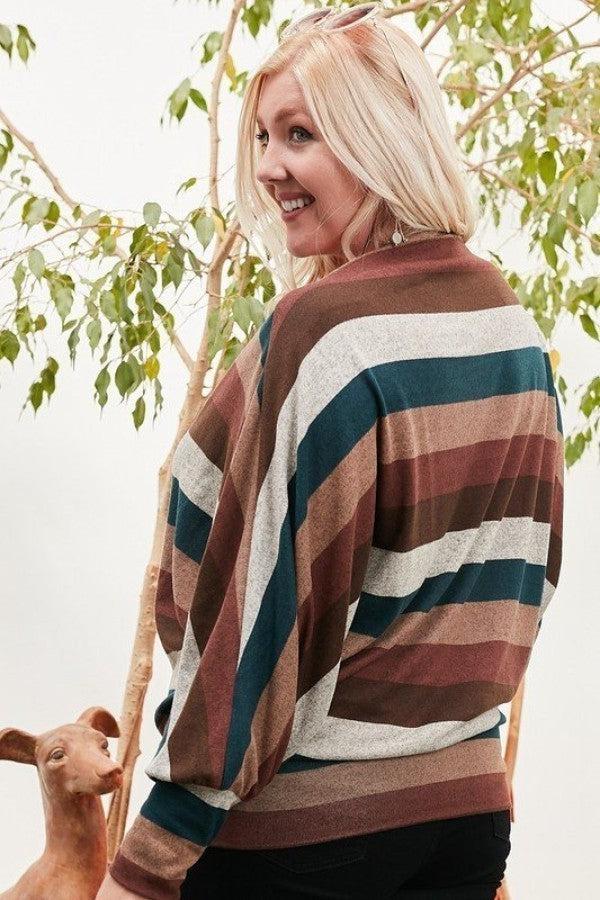 Woman wearing a boat neck multi stripe print knit top with long bubble sleeves in hunter green and brown, posing outdoors.