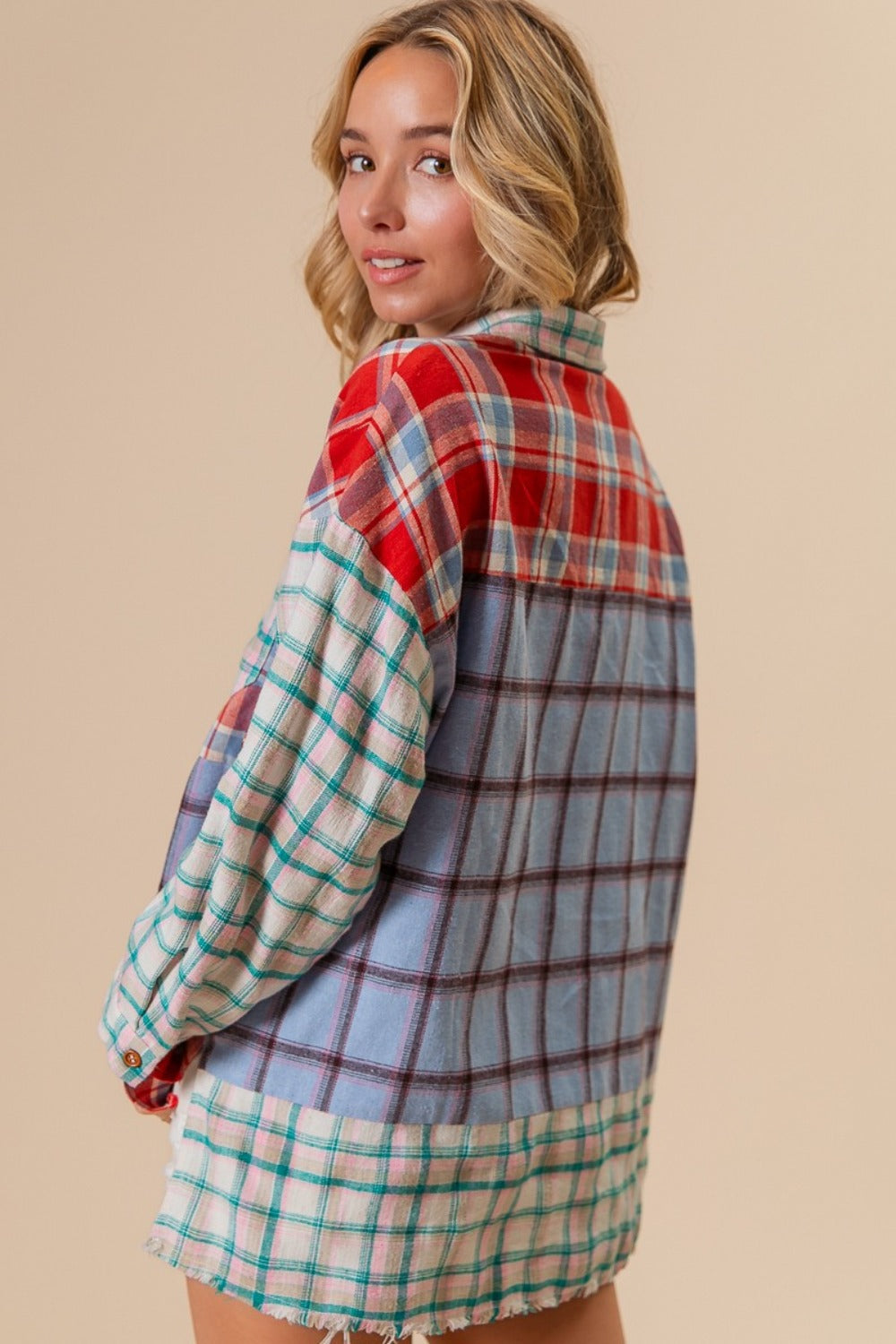 Woman wearing a colorful color block plaid button-down shirt, featuring red, blue, and green patterns, made of 100% cotton.