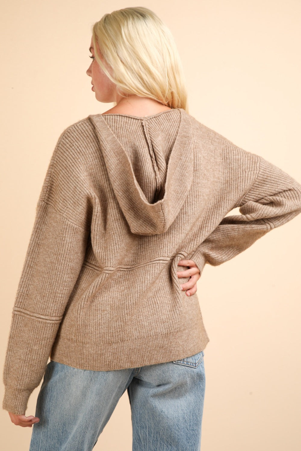 Woman wearing beige seam detail drop shoulder hooded sweater with ribbed texture and slightly stretchy cotton spandex fabric