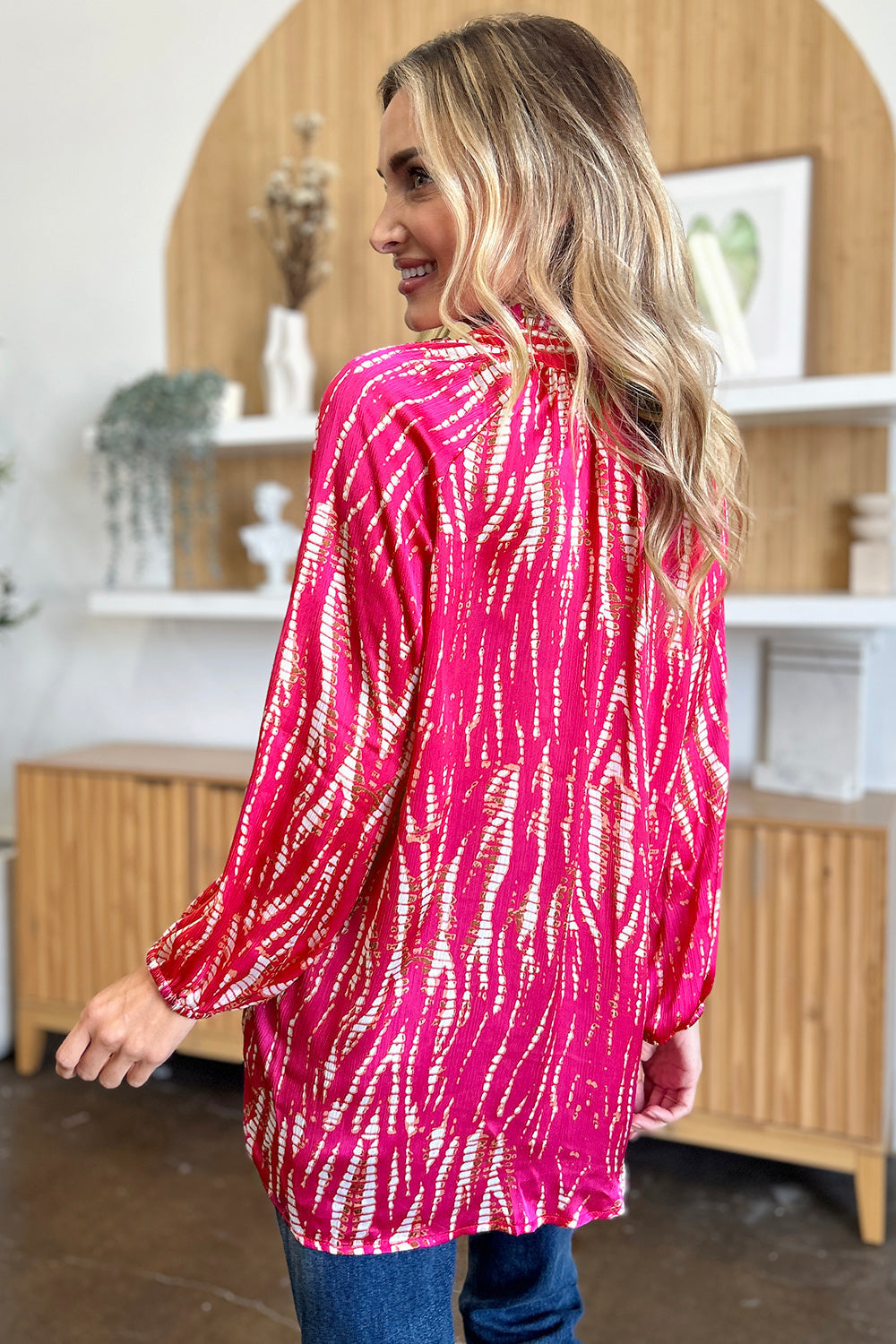 Woman wearing a vibrant printed button-up long sleeve shirt with frill detailing, made from 100% polyester, shown from the back.