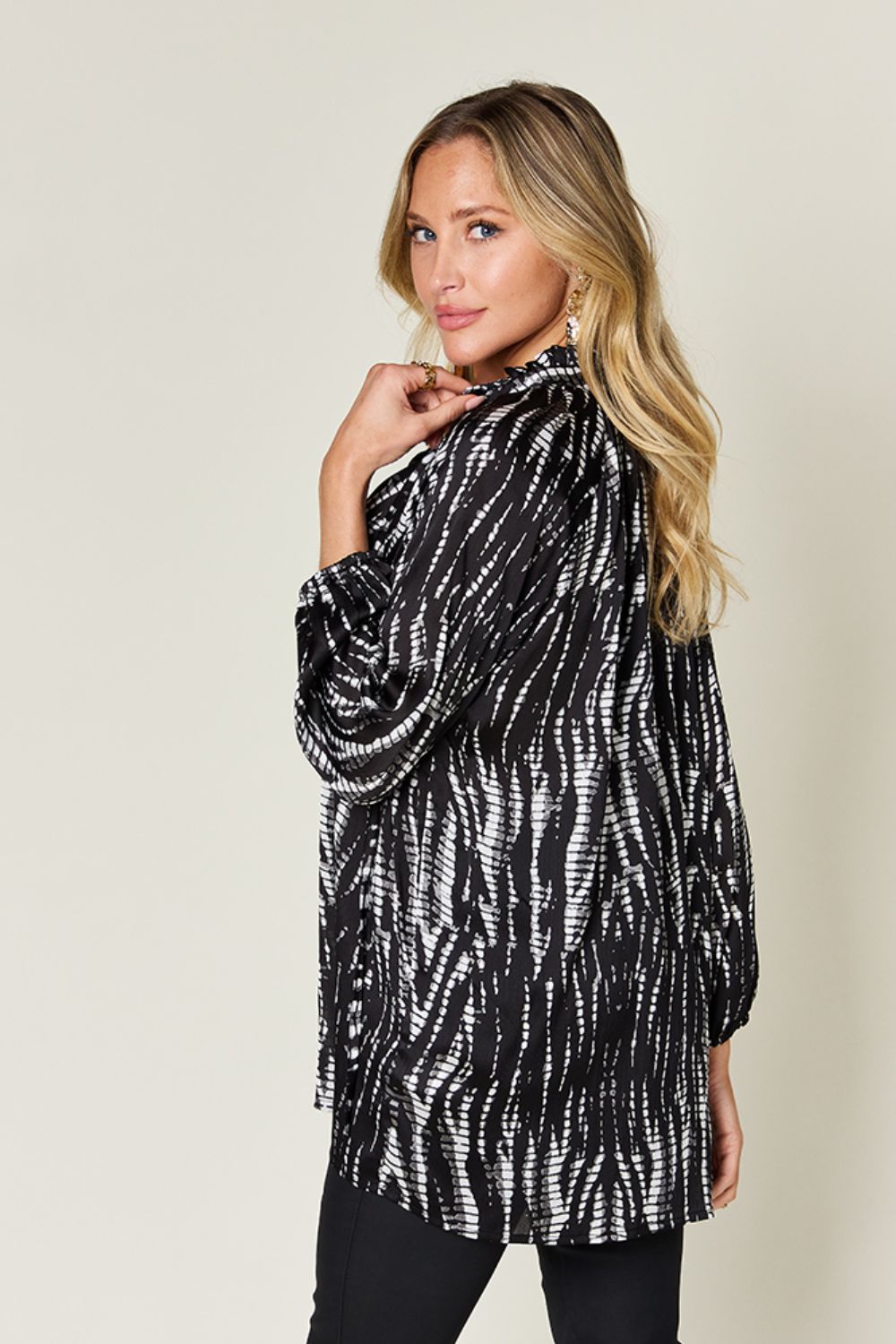 Woman wearing a printed button-up long sleeve shirt with a frill design, black and white pattern, made of 100% polyester.