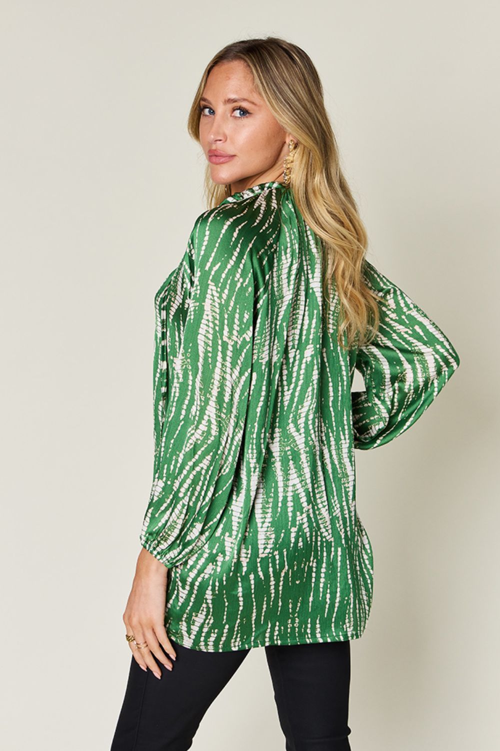 Woman wearing green printed button-up long sleeve shirt in lightweight, opaque polyester with no stretch, shown from the side.