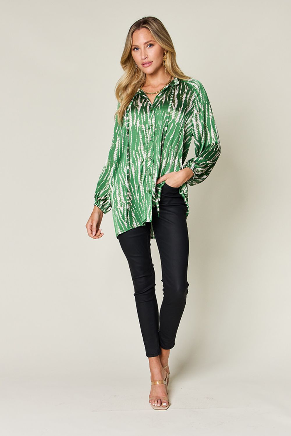 Woman wearing a green printed button-up long sleeve shirt with black pants, featuring frill design and no stretch, made from 100% polyester.