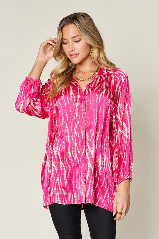 Woman wearing a vibrant pink printed button-up long sleeve shirt made from 100% polyester with a frill design.