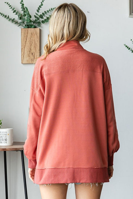 Back view of coral split neck kangaroo pocket sweatshirt with raw hem and long sleeves, made of 100% polyester.