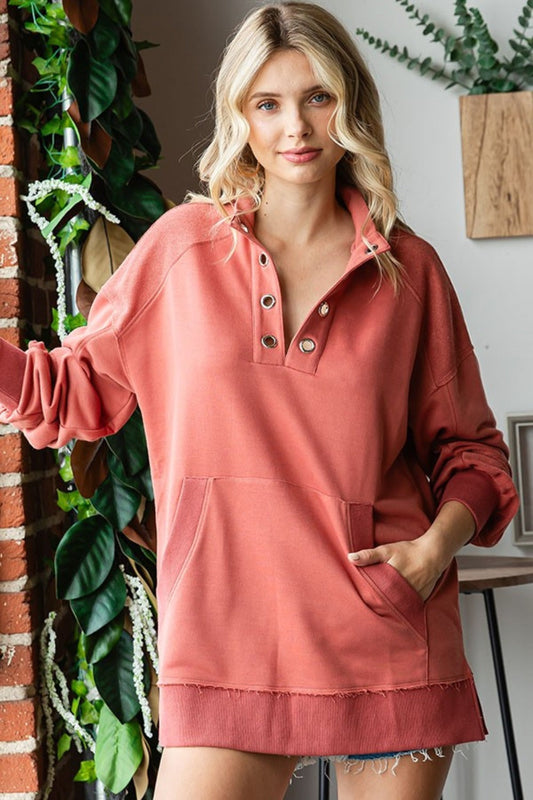 Woman wearing Grommet Split Neck Kangaroo Pocket Sweatshirt with raw hem and slit, made of 100% polyester, opaque material.