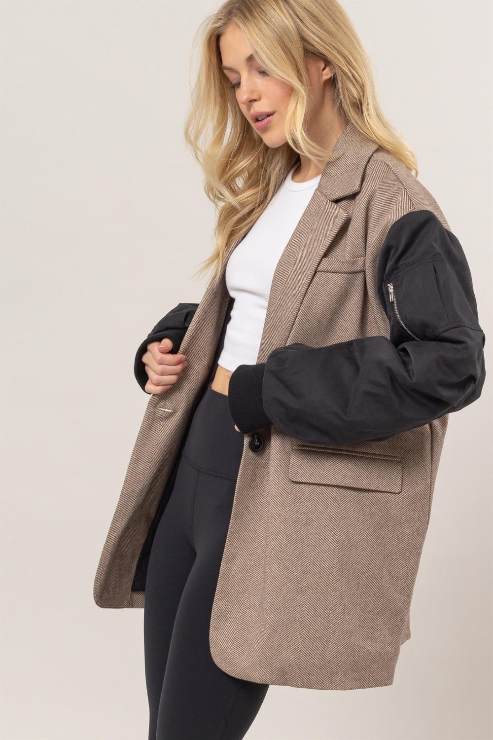 Woman wearing herringbone mixed media contrast long sleeve blazer with buttoned front and lined body.