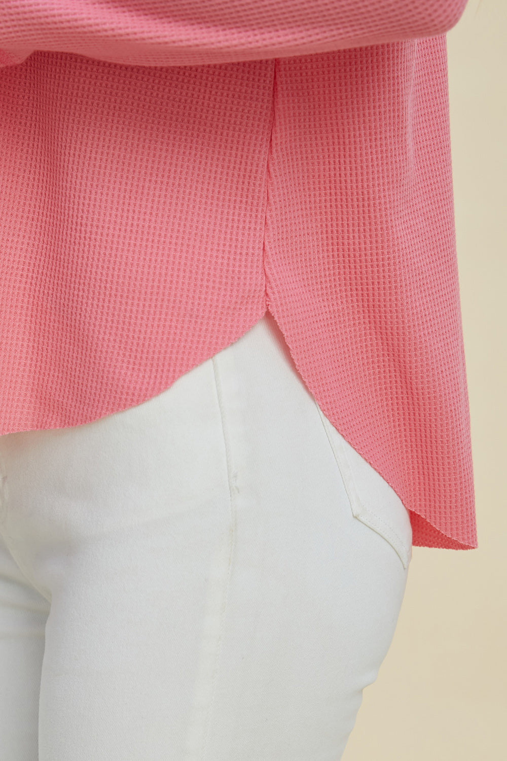 Pink high-low dropped shoulder long sleeve hoodie paired with white pants.