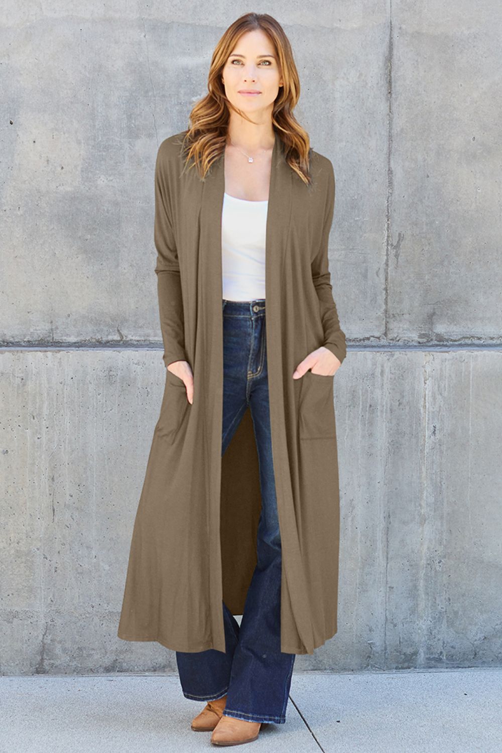 Woman wearing open front long sleeve cover up with pockets, slightly stretchy, opaque material, in taupe color, casual style.