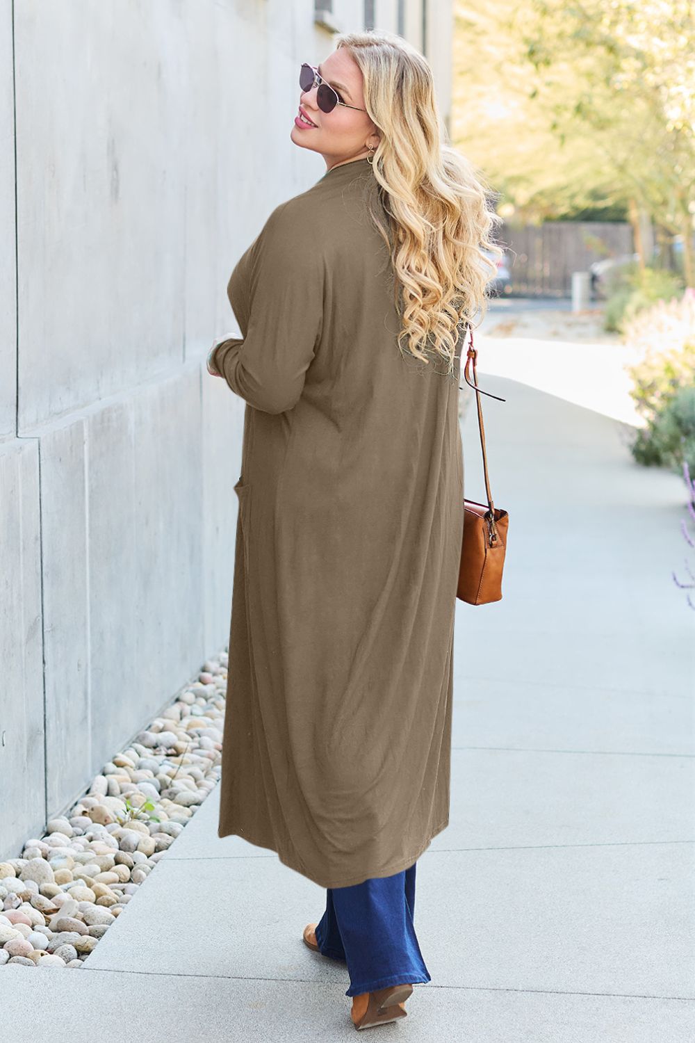 Woman wearing open front long sleeve cover up with pockets, stylish streetwear outfit, slightly stretchy in brown rayon-spandex blend.