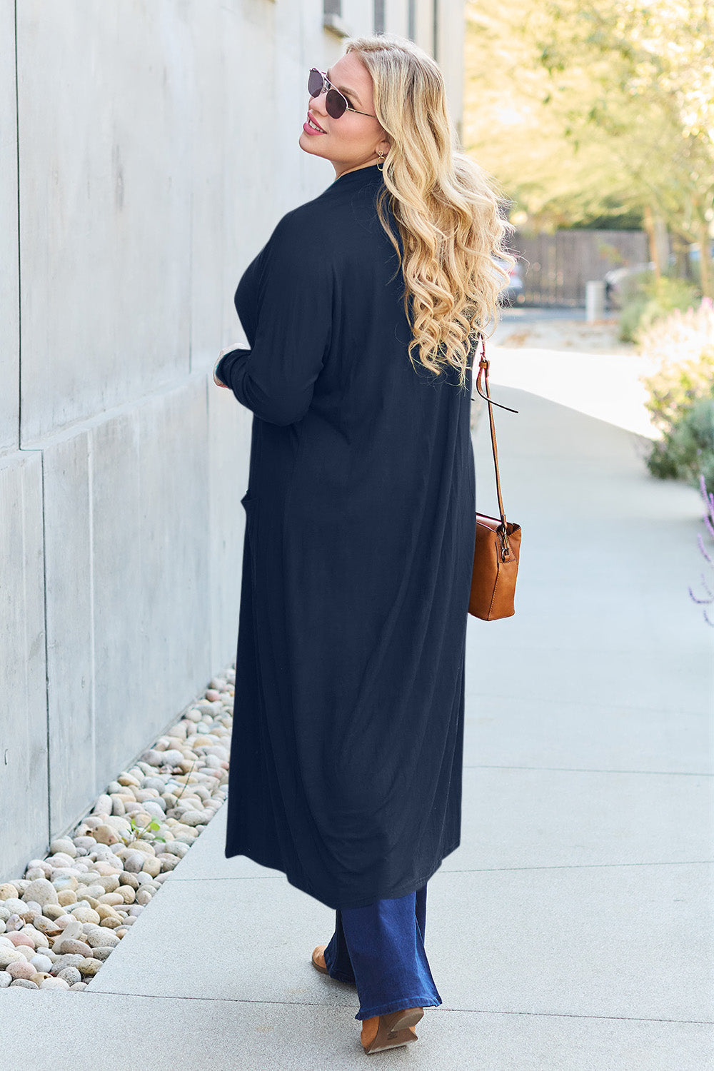 Woman wearing an open front long sleeve cover up with pockets, slightly stretchy opaque material, made of rayon and spandex.