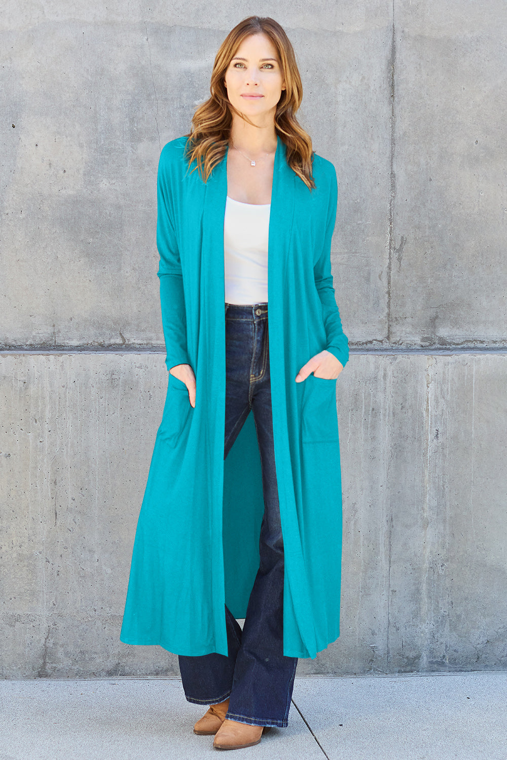 Woman wearing teal open front long sleeve cover up with pockets, paired with jeans, showcasing casual chic fashion style.