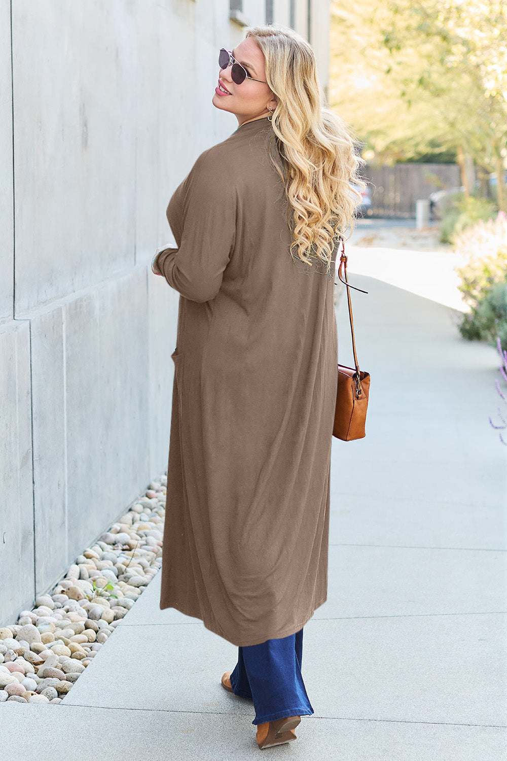 Woman wearing an open front long sleeve cover up with pockets, made of 95% rayon and 5% spandex, stylishly walking outdoors.