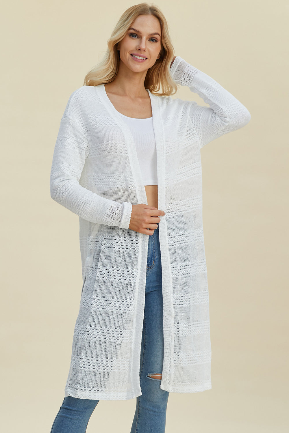 Woman wearing open front longline cardigan with openwork design, in white, featuring moderate stretch and made from 100% polyester.