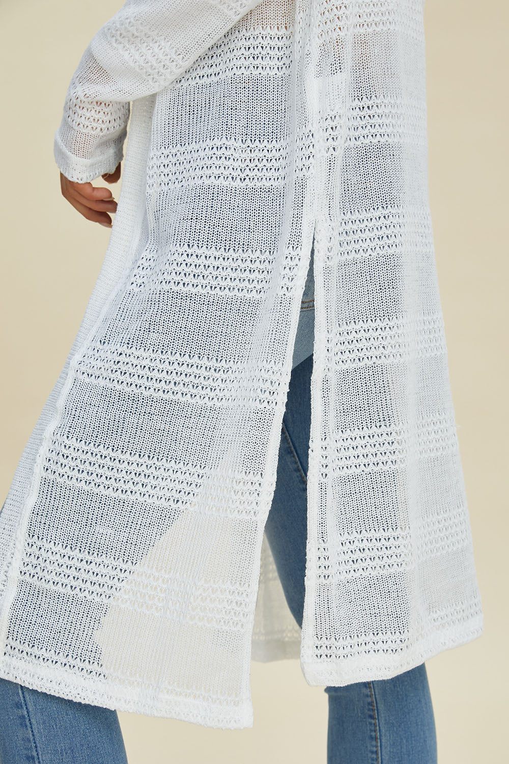 Open front longline cardigan featuring openwork design and moderate stretch, made of 100% polyester, modeled with jeans.