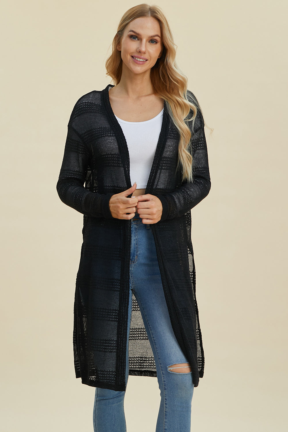 Woman wearing open front longline cardigan with openwork design and moderate stretch in black, made of 100% polyester.