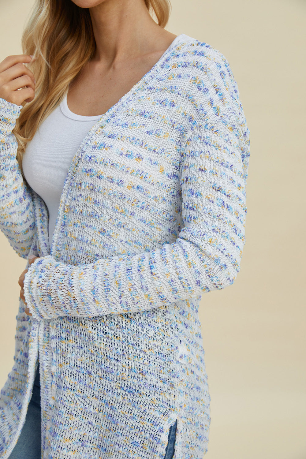 Woman wearing an open front longline cardigan with openwork texture, made of 100% polyester with a moderate stretch.