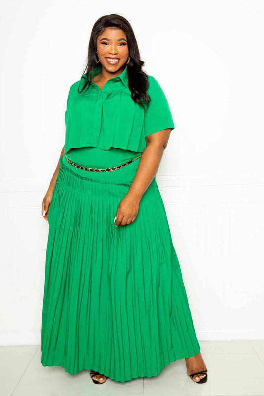 Woman wearing green pleated cropped shirt and maxi skirt set, showcasing plus size fashion with vibrant color and stylish design.