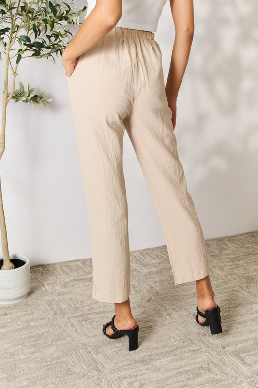 Woman wearing beige pull-on pants with pockets, made from 70% cotton, 28% polyester, and 2% elastane.