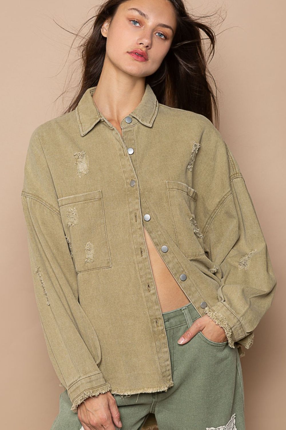 Woman wearing a button down raw hem distressed shacket made of 100% cotton with normal thickness and no lining.