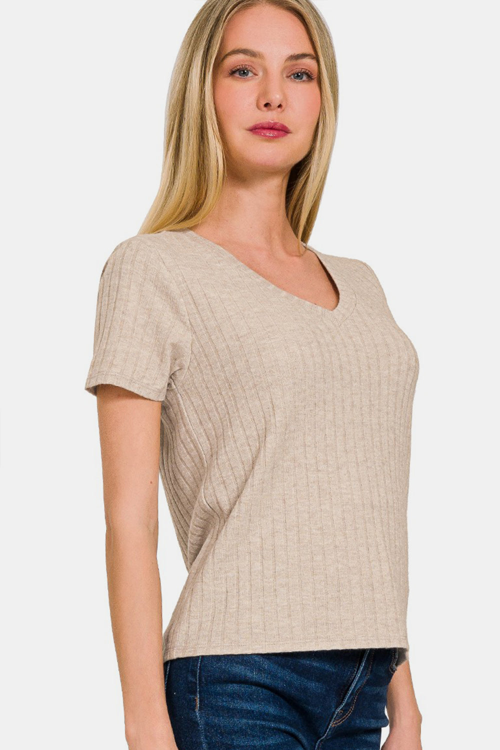 Woman wearing beige ribbed short sleeve t-shirt, featuring opaque material with 50% rayon, 28% polyester, 22% nylon composition.