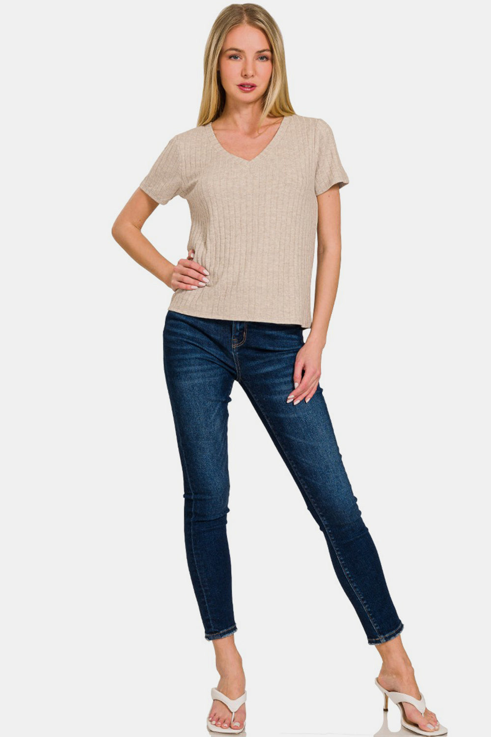 Woman wearing a ribbed short sleeve t-shirt with v-neck, paired with dark blue jeans and white heels.