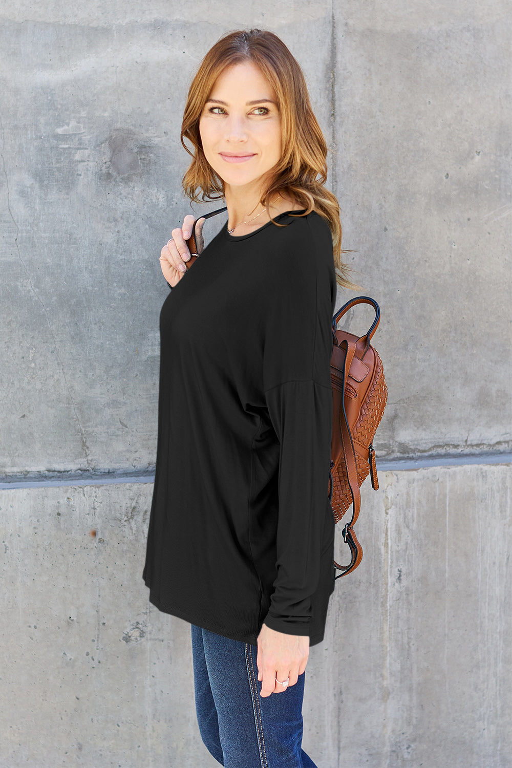 Woman wearing black round neck dropped shoulder T-shirt with backpack, casual and stylish look.