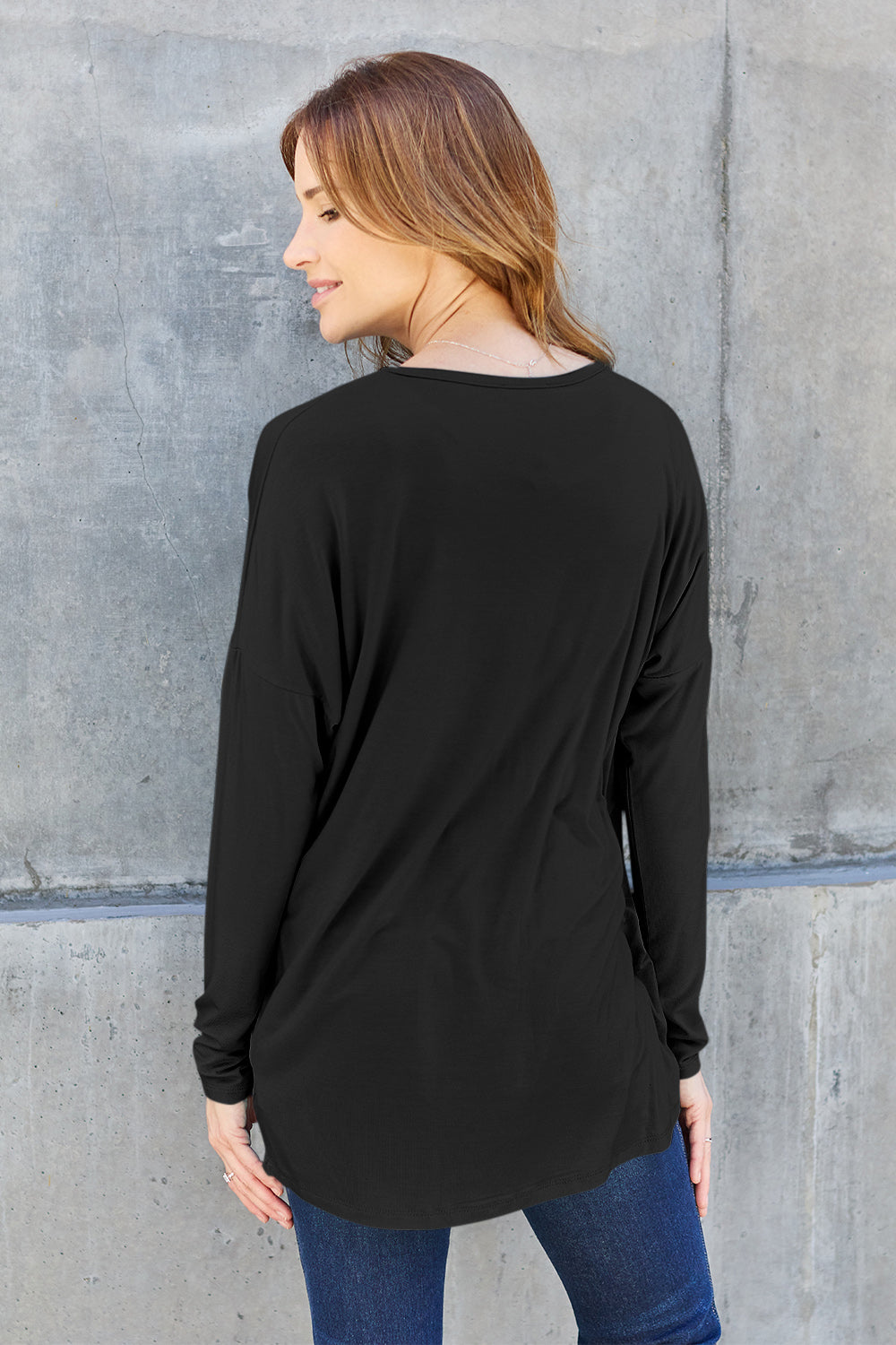 Woman wearing a black round neck dropped shoulder t-shirt made of rayon and spandex, slightly stretchy and opaque.