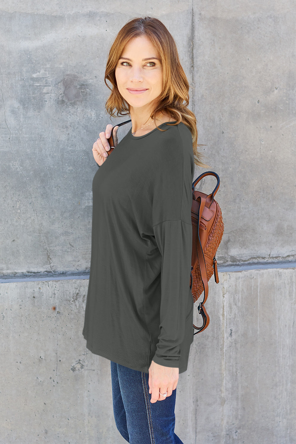 Woman wearing a round neck dropped shoulder t-shirt with a backpack, showcasing a casual and basic style.